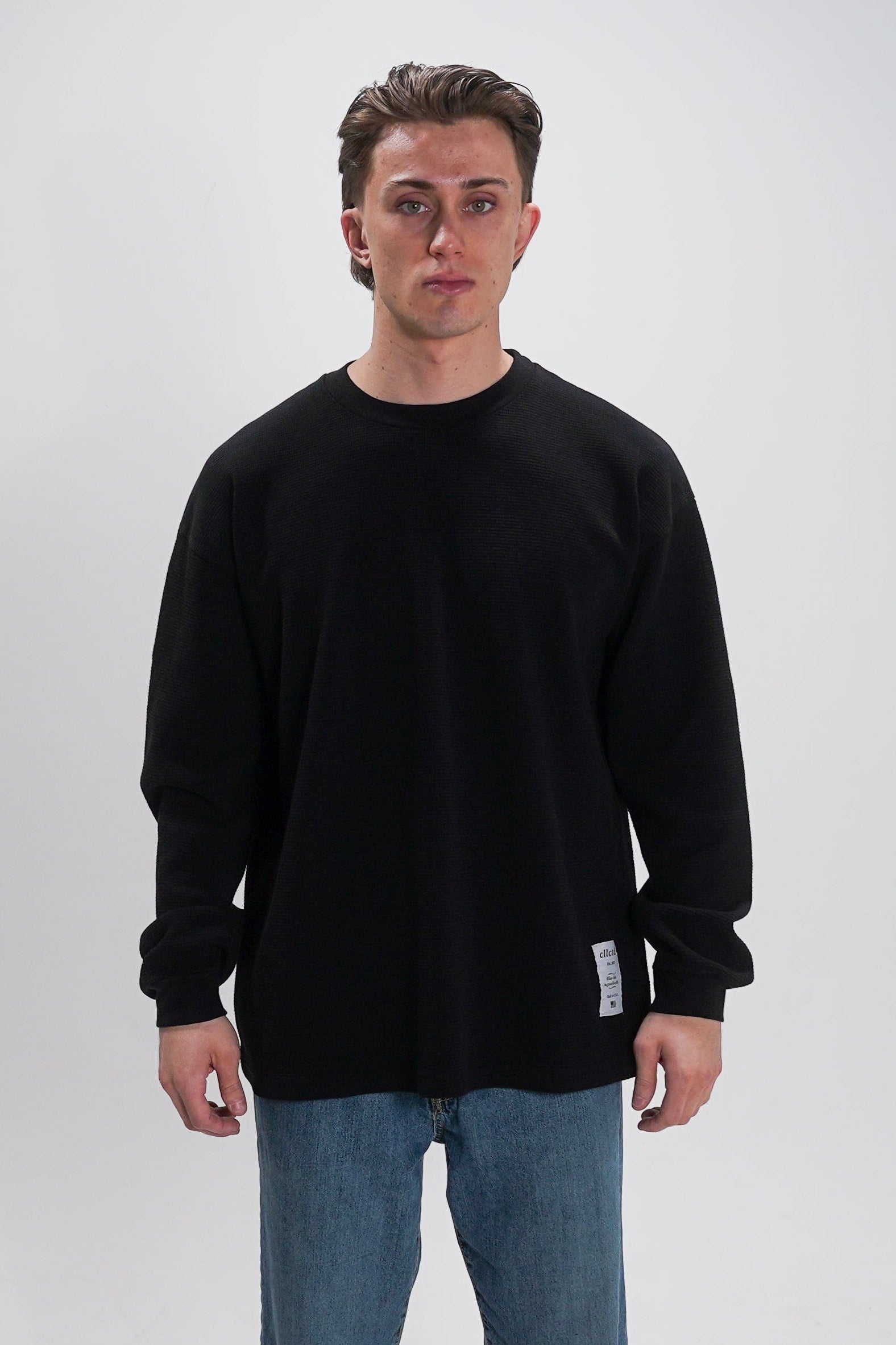 Man wearing a black sweater and blue jeans on a white background